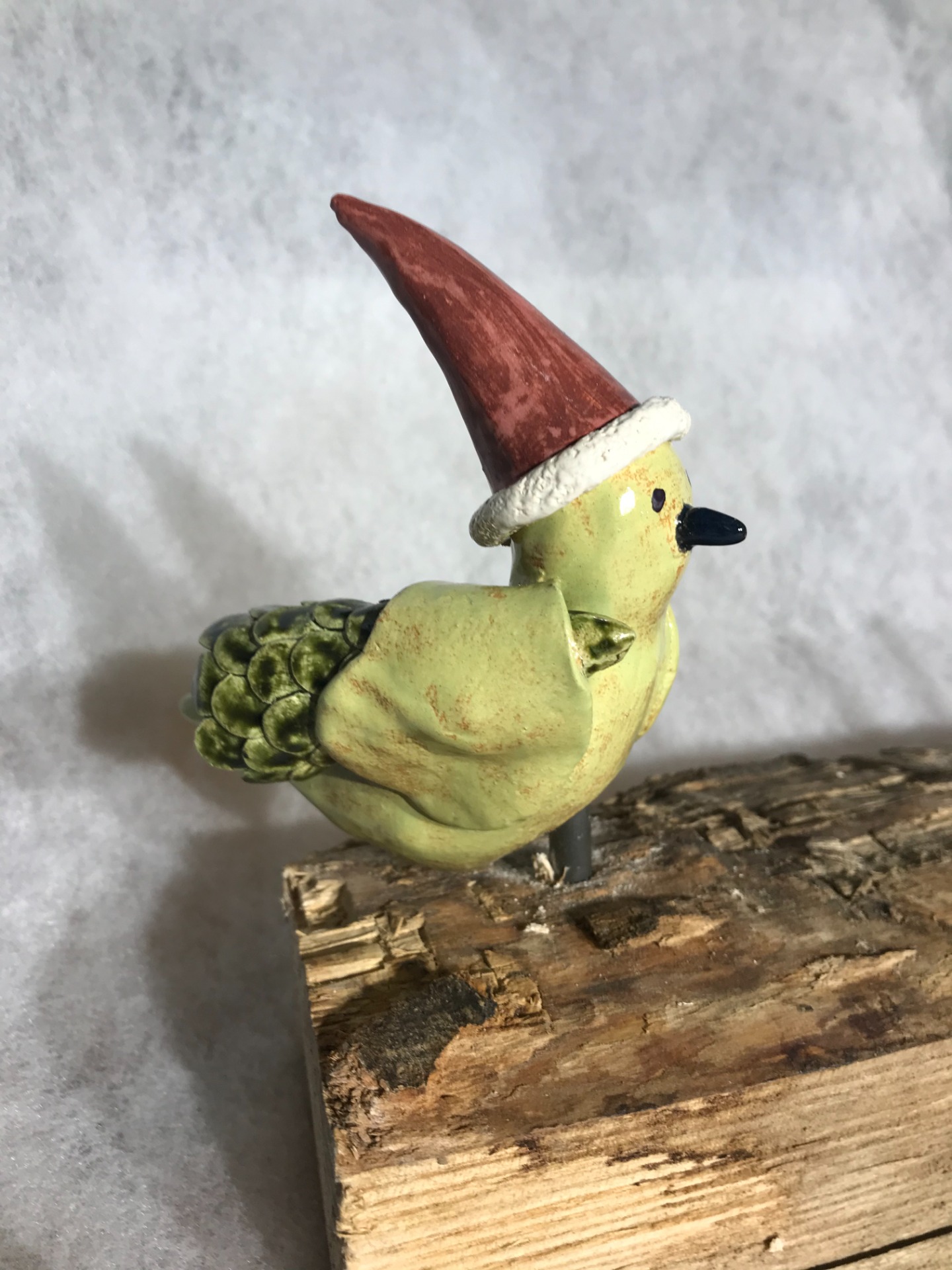 Keramische vogel met kerstmuts op boomstammetje